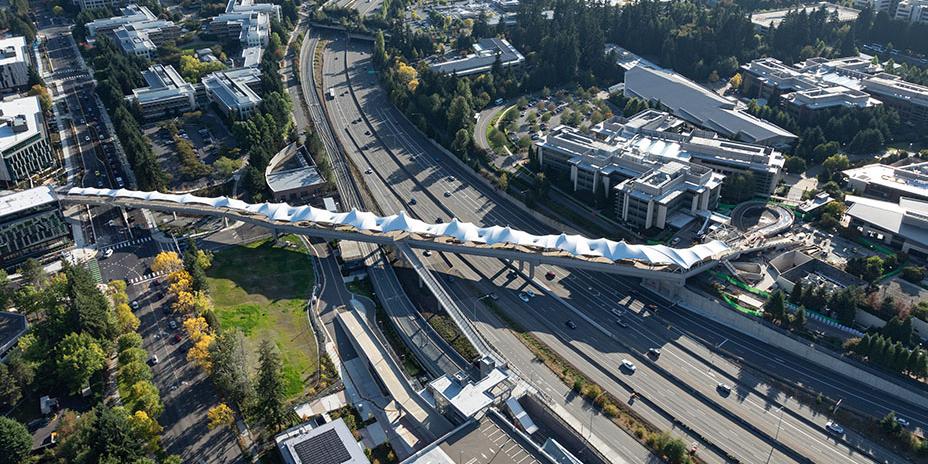 Aerial photo showing freeway, light rail line, and pedestrian overpass.